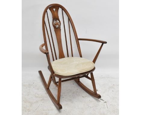 An Ercol stained beech rocking chair, the splat pierced with a central oval depicting a swan.Additional InformationThe seat w