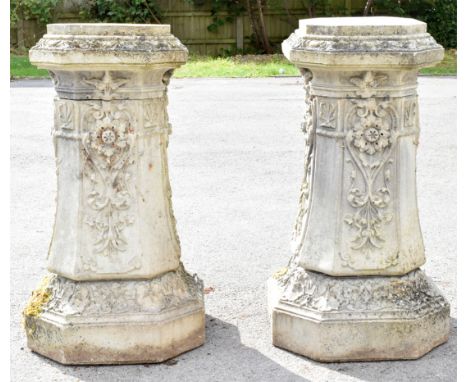 A pair of reconstituted stone garden columns, of swept octagonal form, moulded with floral detailing, height 96cm, width at b