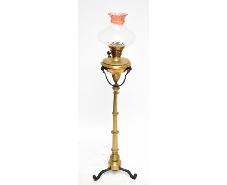 An early 20th century Arts &amp; Crafts brass and iron standard oil lamp, with detachable brass reservoir and clear glass sha