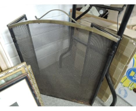 A vintage brass and cast fire guard with mesh screen