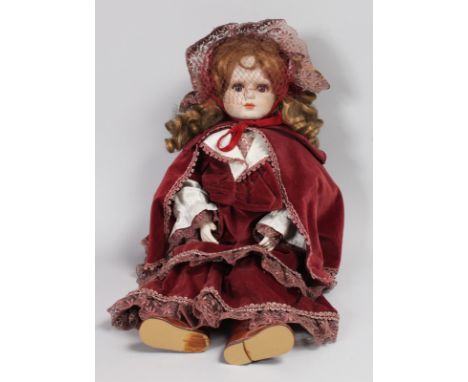 A GOOD GERMAN BISQUE HEADED DOLL wearing a velvet cloak.