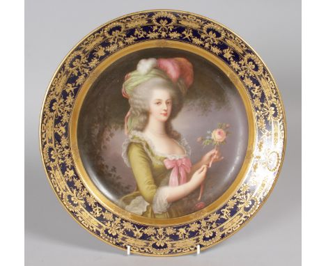 A LARGE 19TH CENTURY VIENNA CIRCULAR DISH, painted with a portrait of a pretty young lady holding a rose, within a gilded bor