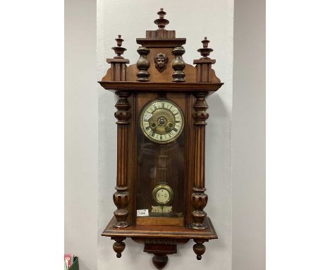 A XIX Century Walnut Vienna Wall Clock, the applied top with turned finials, case with an arched glazed door, round dial with