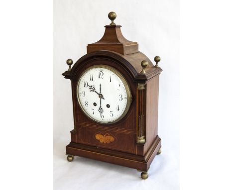 AN EDWARDIAN MAHOGANY CASED MANTEL CLOCK with boxwood string inlay, a convex white enamel face and brass bezel and feet. 18in