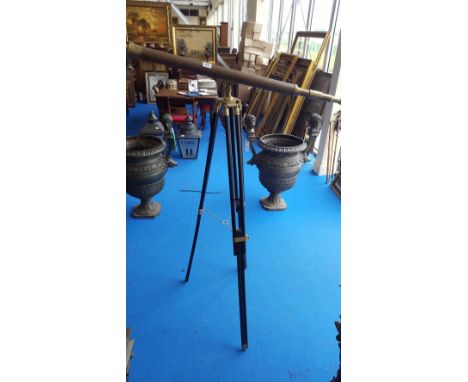 A LARGE BRASS TELESCOPE ON AN EBONISED TRIPOD BASE.