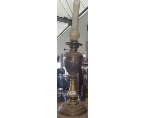 AN EARLY 20TH CENTURY OIL LAMP with an embossed and engraved reservoir on conforming base and a brass column, converted.