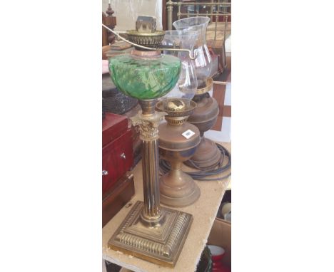 A 19TH CENTURY BRASS COLUMNED OIL LAMP with green glass bowl, along with two other oil lamps.