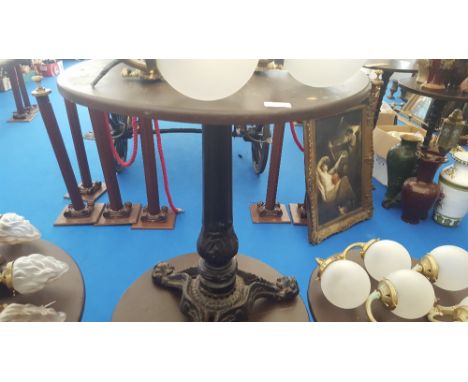 A SMALL CIRCULAR BAR TABLE with heavy decoration and cast iron tripod base.  (Used in Limehouse Café).