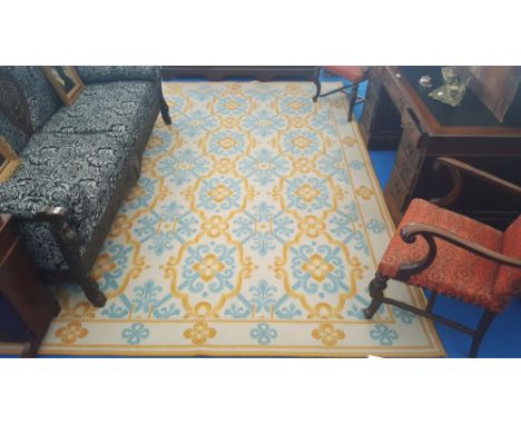 A CLASSICALLY DECORATED CREAM GROUND CARPET with all-over fleur de lis incorporated decoration in blue and gold. 11'5" x 8'2"