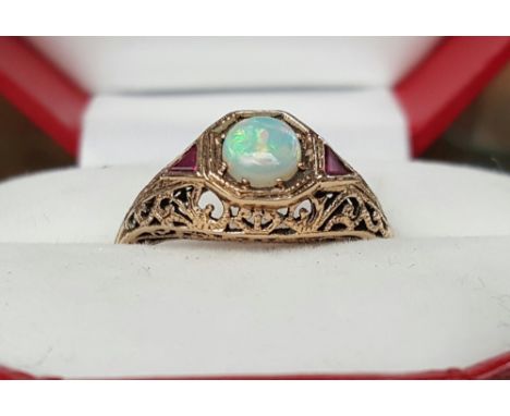 A 9ct GOLD OPAL & RUBY SET LADY'S RING in an ornate setting.