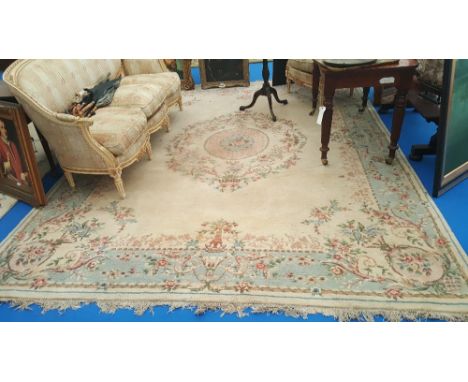 A LARGE CREAM GROUND CARPET with pink floral medallion and wide blue border. 11'10" x 9'.