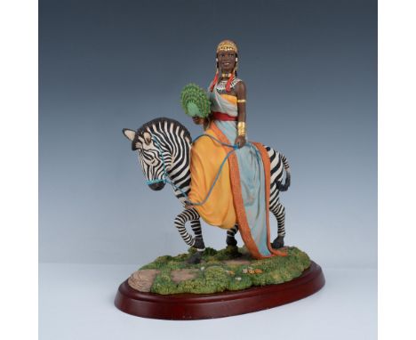 This is a wonderfully elaborate sculpture of a beautiful African woman riding on a zebra. She is adorned in gold, and fashion