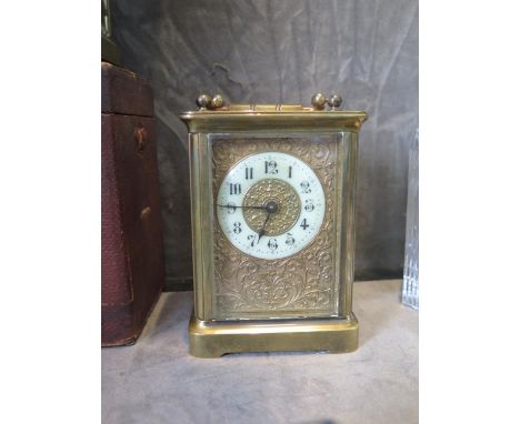 An Edwardian brass carriage timepiece clock, the floral scroll decorated dial with enamelled chapter ring, the single train m