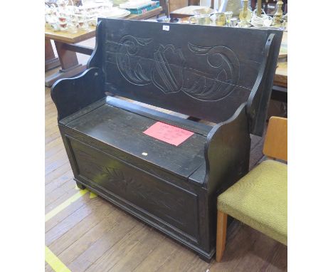 A carved oak monks bench, the hinged top over a lidded seat with lozenge carved front, 106 cm wide, 93 cm high 