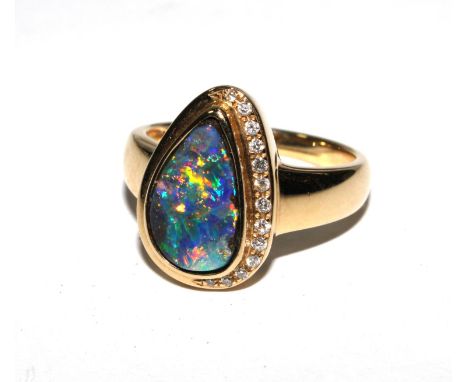 A yellow dress ring with a free form pear shaped 'black' boulder opal and round brilliant cut diamonds 