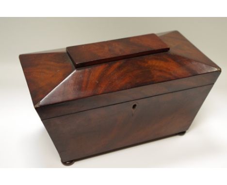 An early Victorian mahogany sarcophagus tea caddy, hinged cover enclosing a bowl aperture and a pair of lidded compartments, 