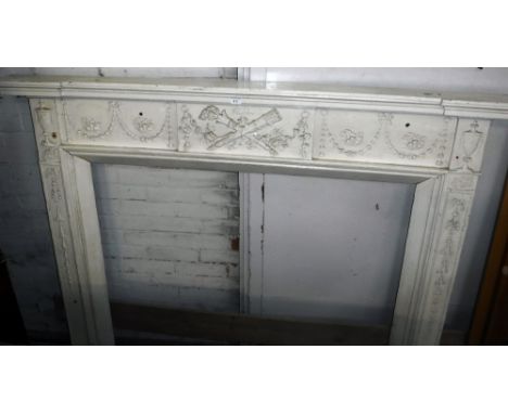 AN ADAM STYLE PINE AND WHITE PAINTED FIRE SURROUND with urns, floral swags and trophy decoration, probably 19th century, 54.5
