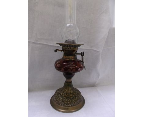 Decorative ruby glass table lamp on circular brass base with chimney