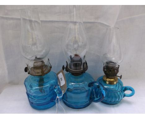 3 light blue handled glass based oil lamps each with glass chimney