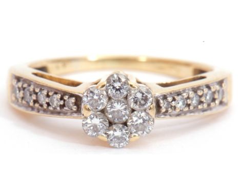 Diamond cluster ring, a design featuring a brilliant cut diamond cluster, raised above diamond set shoulders to a plain polis