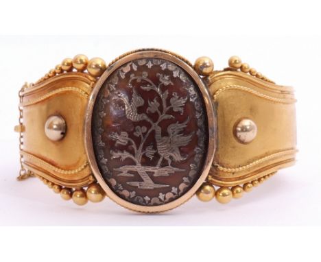 Victorian Etruscan hinged bangle, the top section centring a large oval pique panel inlaid with a silver bird and branch in f