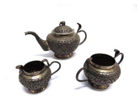 A WHITE METAL INDIAN THREE PIECE TEA SERVICE  embossed profusely with flora and with Cobra handles