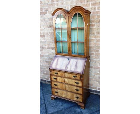 A REPRODUCTION BUREAU BOOKCASE  the double arched bookcase top above bureau with fitted interior, four drawers and ogee brack