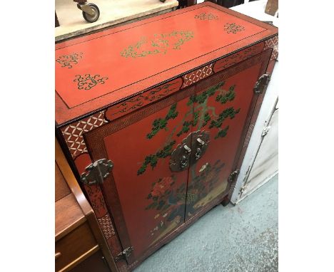 A Oriental red lacquered cupboard, depicting a peacock amongst foliage, two doors with single shelf, 64x31x95cm 