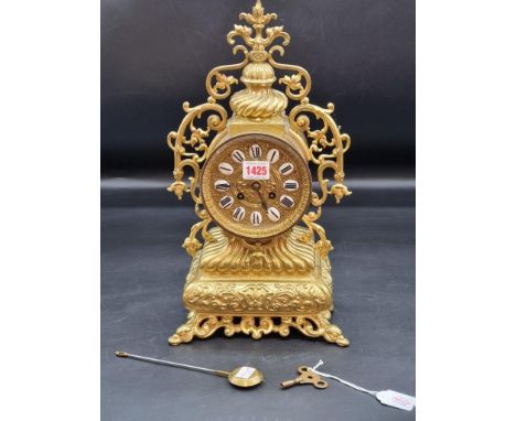A brass mantel clock,&nbsp;with enamel chapter ring, 41.5cm high, with pendulum and winding key.&nbsp; 