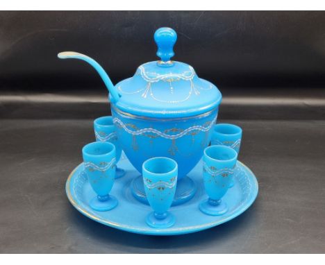 A late 19th century opaque blue glass punch set, comprising: a bowl and cover, 29.5cm high; stand; ladle; and six goblets. 