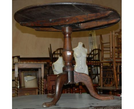 An early 19th century circular oak tilt-top pedestal tripod table