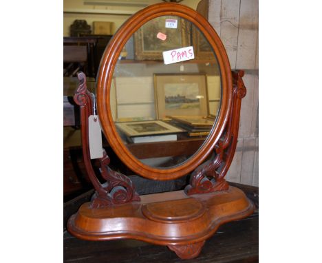 A mid Victorian mahogany oval swing dressing table mirror, raised on a shaped base with hinged compartment