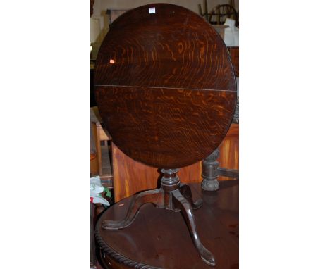 An early 19th century circular oak tilt-top pedestal tripod table, dia.76.5cm