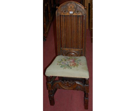 An antique joined and low relief carved oak slatback single dining chair, having floral tapestry upholstered stuffover seat 