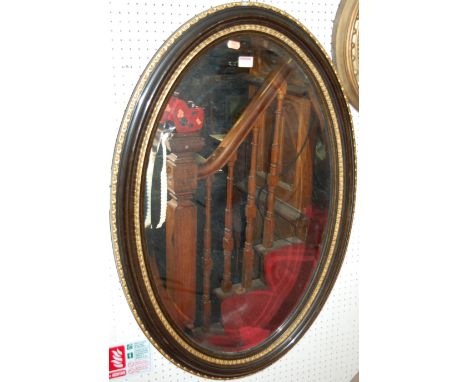 A circa 1900 ebonised and gilt gesso framed oval wall mirror