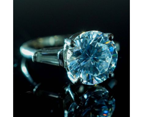 This elegant sterling silver ring features a striking round-cut cubic zirconia center stone with a subtle bluish tint, secure