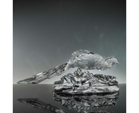 Clear crystal sculpture is depicted in a striding pose atop a stylized rocky terrain base, with elongated tail feathers exten