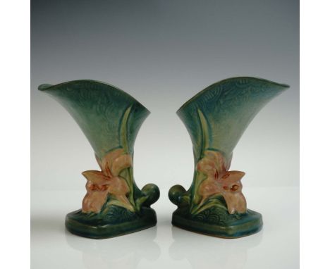 A lovely pair of cornucopia pottery vessels designed with blossoms of rose coloration set on a green ground with pool ripplin
