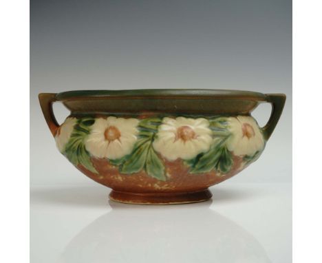 The vase is decorated with a continuous relief of daisy-like blossoms, each with a brown center and creamy-colored petals. Su