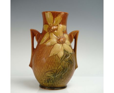 Enamoring pottery vase adorned with raised clematis blossoms in soft yellow tones with sculpted green leaves and vines that s