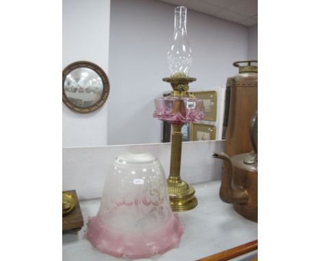 A Brass Oil Lamp Circa 1900, with fluted base and support, cranberry tinted frill glass well and associated shade.