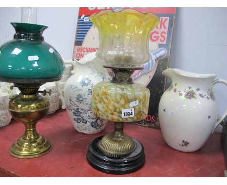 An Early XX Century Oil Lamp, with black glaze terracotta base, mottled glass well and yellow tinted shade, another oil lamp,