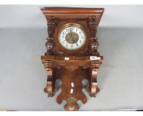 A decorative German ‘wag on the wall’ Freischwinger clock, the walnut case with turned columns and applied carved leaves, whi