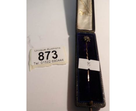 A fine cased gold stick pin with a diamond set flower head