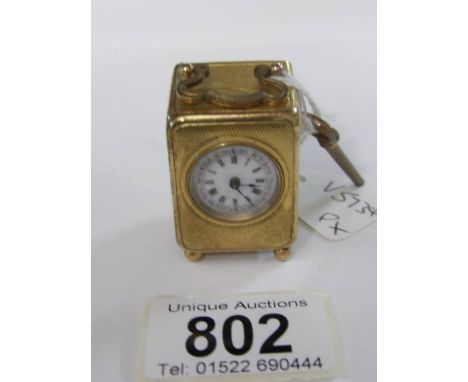 A miniature French brass carriage clock with enamel dial and complete with key