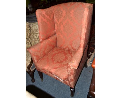 ^ A George III wingback armchair, early 19th century, recovered in salmon coloured fabric, rounded arms and a squab cushion, 