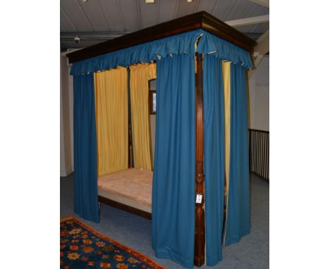 A four poster bedstead with reeded and carved foot posts, hung with blue curtains lined in yellow, height 231cm