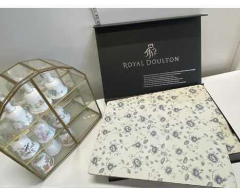 A small glazed display case with collection of ceramic bells and Royal Doulton placemats, shipping unavailable