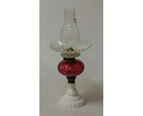 An opaline glass pedestal oil lamp, having cranberry glass font
