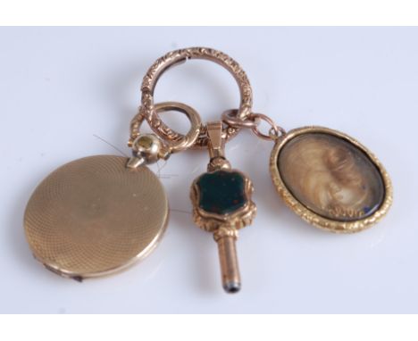 A Victorian engine turned yellow metal picture locket; together with a yellow metal and agate set watch key; and a yellow met